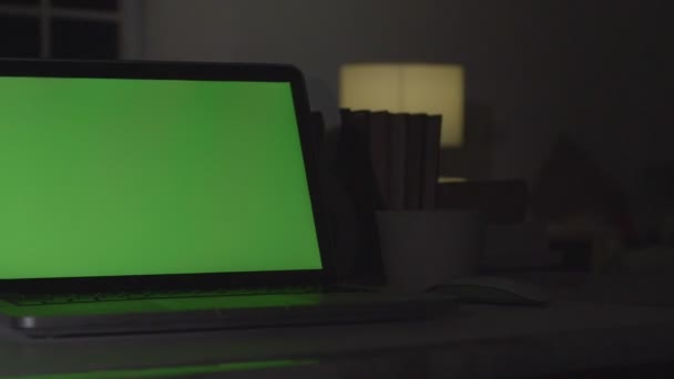 緑色の画面を備えたラップトップ 暗いオフィスだドリーが撃たれたあなた自身の画像やビデオを置くのに最適 — ストック動画