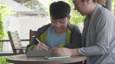 Asyalı çocuk tablet bilgisayar oynuyor ve annesi ile konuşuyor , gülümseme yüz.