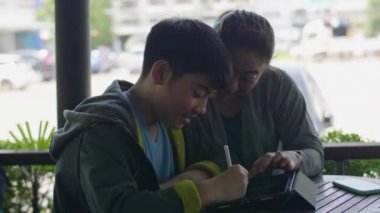 Asyalı çocuk tablet bilgisayar oynuyor ve annesi ile konuşuyor , gülümseme yüz.