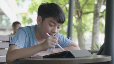 Tablet bilgisayar kullanarak Sevimli asya çocuk , Genç genç çocuk sessizce yüz ile dijital tablet üzerinde ev ödevi yapıyor .