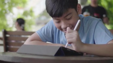 Tablet bilgisayar kullanarak Sevimli asya çocuk , Genç genç çocuk sessizce yüz ile dijital tablet üzerinde ev ödevi yapıyor .
