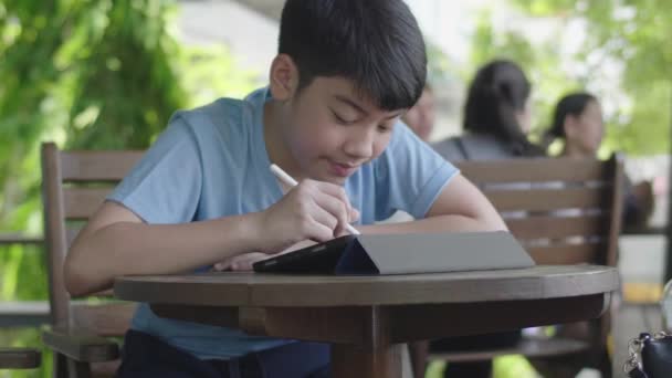 可爱的亚洲男孩使用平板电脑 年轻的十几岁的男孩做家庭作业的数字平板电脑与沉默的脸 — 图库视频影像