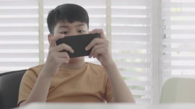 Asyalı çocuk cep telefonu oynuyor 