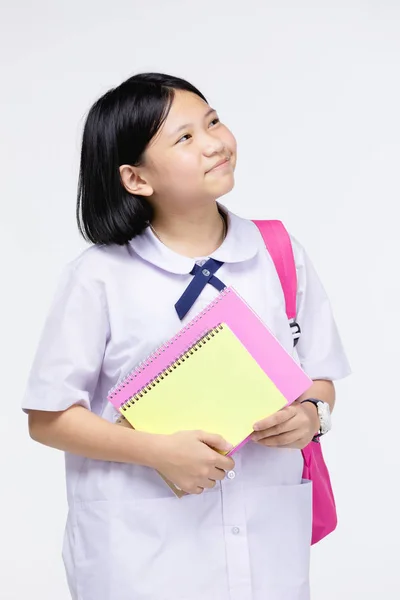 Menina bonito no uniforme do estudante com artigos de papelaria em fundo cinza — Fotografia de Stock