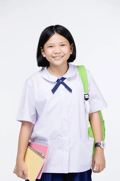 Roztomilá dívka v uniformě studentky s papírnictví na šedé barvě backgroun — Stock fotografie