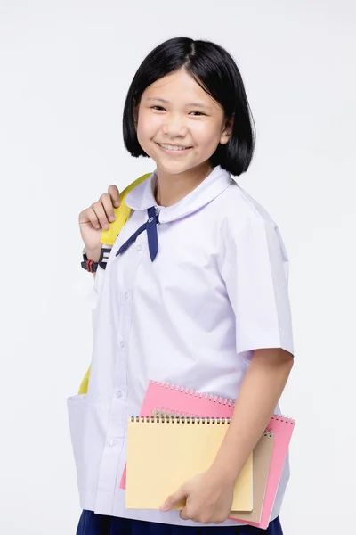 Menina bonito no uniforme do estudante com artigos de papelaria em fundo cinza — Fotografia de Stock