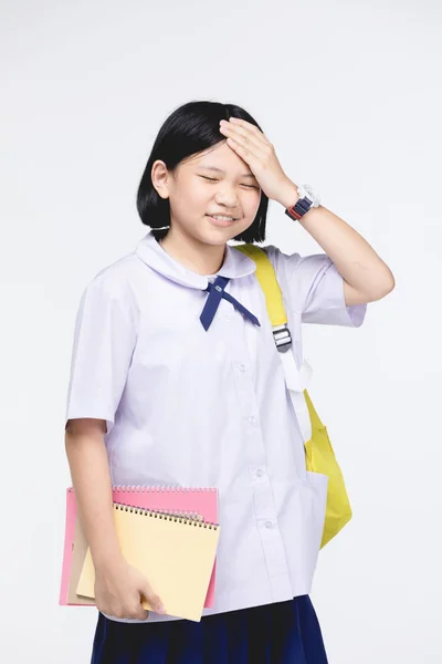 Söt flicka i elevens uniform med brev papper på grå bakgrunds — Stockfoto