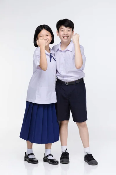 Aasian girl and boy in student's uniform on gray background. — Stock Photo, Image