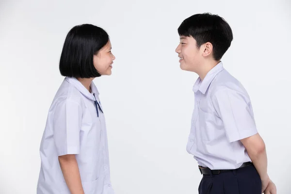 Aasian girl and boy in student's uniform on gray background. — Stock Photo, Image