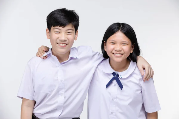 Aasian girl and boy in student 's uniform on gray background . — стоковое фото