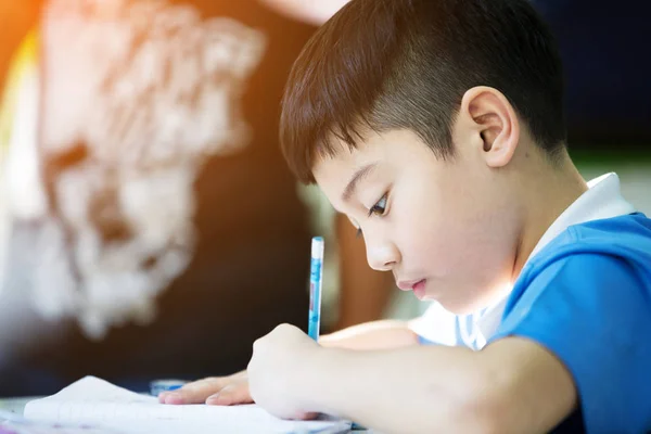 Giovane asiatico ragazzo doing suo homework — Foto Stock