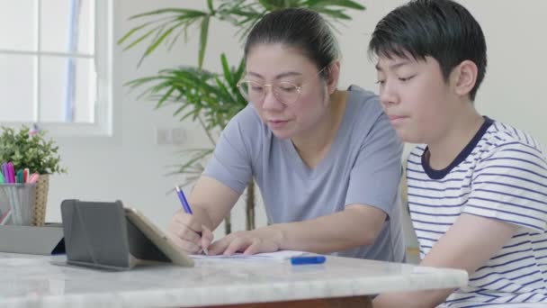 妈妈帮儿子在家做作业 美丽的母亲一起在家里读课本和与儿子聊天 — 图库视频影像