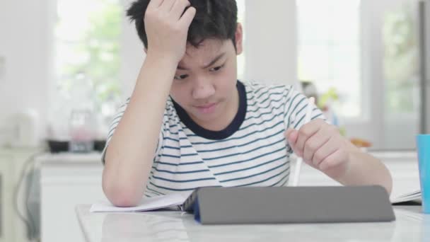 这个脾气暴躁的亚洲男孩用平板电脑做功课来查找信息 — 图库视频影像