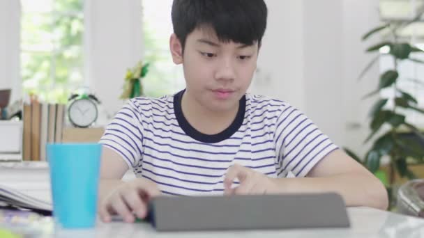 Azjatycki Chłopak Siedzi Krześle Domu Pracy Domowej Pomocą Tabletu Aby — Wideo stockowe