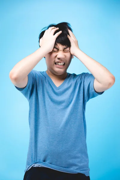 Portret van boze Aziatische jongen op blauwe achtergrond. — Stockfoto