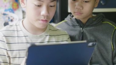 Mutlu küçük çocuk tablet bilgisayar ile ödevini yapıyor. Evde ki masada oturan ve arkadaşıyla ev ödevini yapan çocuk. Okul, çocuk, eğitim kavramı.