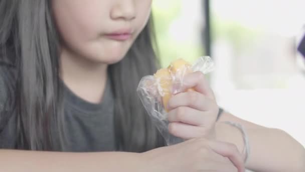 可爱的亚洲小女孩穿着休闲的衣服坐在享受阅读书和吃一块蛋糕在咖啡馆 — 图库视频影像