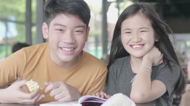 만화책으로 휴식을 취하는 아시아 소년과 귀여운 아시아 어린이 얼굴카페에서 — 비디오