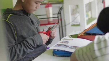 Asyalı çocuk evde makas kağıt kesme.