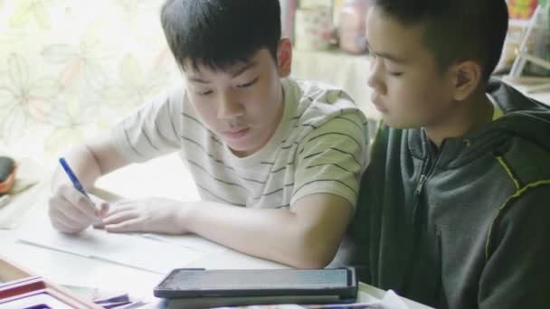タブレットコンピュータで宿題をしている幸せな小さな男の子 子供は家の机に座って 友達と宿題をしています 教育の概念 — ストック動画