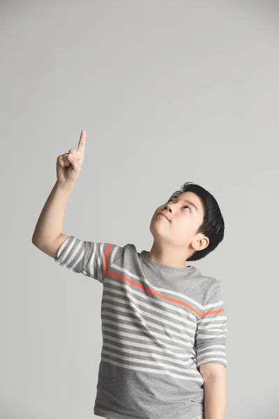 Młody Asian chłopiec myślenia i wskazując podczas uśmiechnięty z Copy Sp — Zdjęcie stockowe