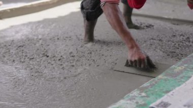 Anonim Beton İşçisi Islak Kaldırımı Yumuşatıyor. Dökülen Beton. Bir fabrika işçisi zeminde ıslak betonu düzleştirmek için kürek kullanır.