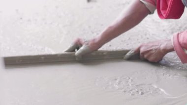 Anonim Beton İşçisi Islak Kaldırımı Yumuşatıyor. Dökülen Beton. Bir fabrika işçisi zeminde ıslak betonu düzleştirmek için kürek kullanır.