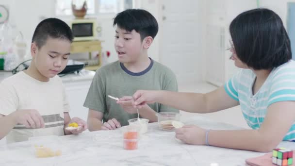 幸せなアジアの子供は笑顔で自宅で食べて楽しむ — ストック動画