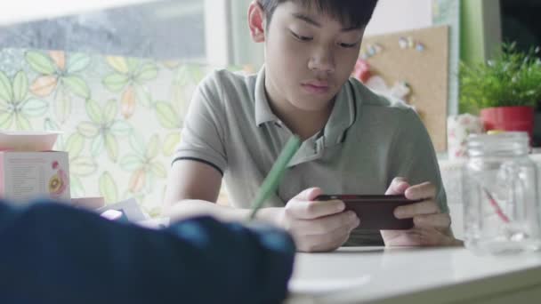 タブレットコンピュータで宿題をしているアジアの男の子 友人と自宅でデジタルタブレットを使って勉強するティーンエイジ ボーイズ — ストック動画