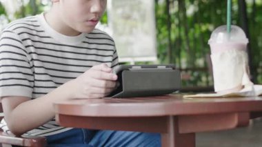 Asyalı çocuk gülümseme yüzü ile tablet bilgisayarda oynuyor.