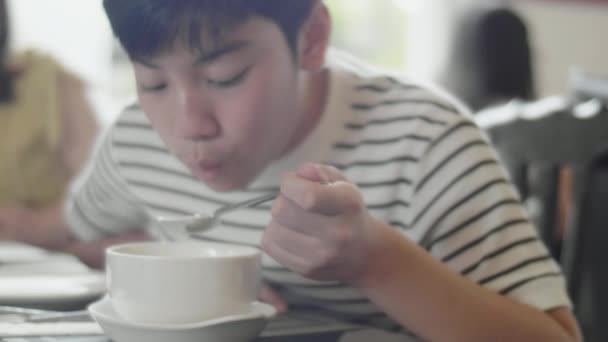 幸せなアジアの男の子は笑顔でレストランで昼食を食べて楽しむ — ストック動画