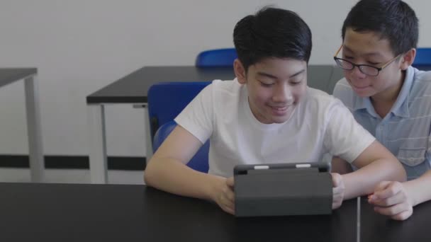 Ασιάτες Έφηβοι Που Χρησιμοποιούν Υπολογιστή Ταμπλέτας Στη Βιβλιοθήκη Δύο Αγόρι — Αρχείο Βίντεο