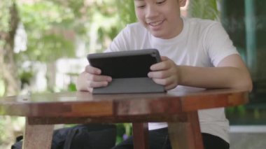 Asyalı çocuk gülümseyen yüzüyle tablet oynuyor..