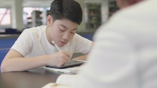 亚洲青少年在图书馆使用平板电脑 两个男孩笑着在平板电脑上画画 — 图库视频影像