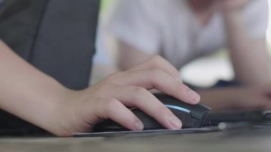 Küçük bir çocuğun eli siyah fare kullanıyor. Yakından bir erkek eli hafif bir farenin tekerleğini kaydırıyor. Adamın kolu şık fare tuşlarına tıklıyor. Kapat.. 