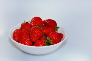 Beyaz bir backgrownd üzerinde beyaz bir tabak çilek 