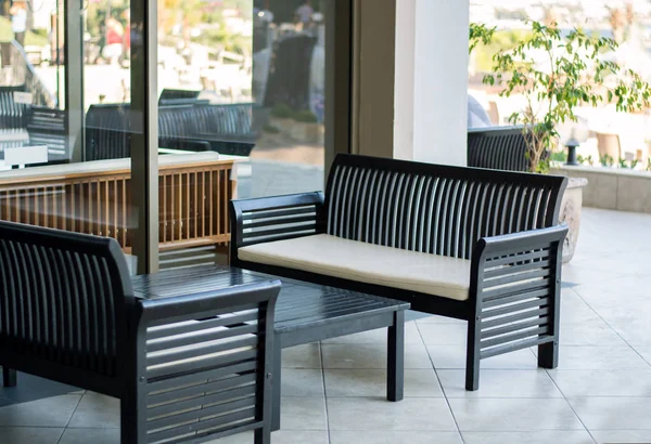 Açık havada dinlenme ve iş görüşmeleri için ahşap karanlık koltuklar rahat tablolarla