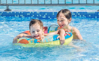 Ablası ve küçük kardeşi açık çocuk havuzunda yüzmek