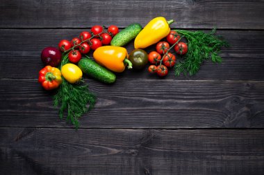 Koyu ahşap zemin üzerinde vitamin açısından zengin çok renkli sebzeler dalın ortasında yer almaktadır. Sağlıklı lif diyeti üst görünümü