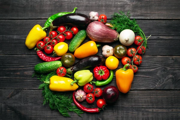 Fresh multi-colored vegetables rich in vitamins on a dark wooden background are located in the middle in the shape of a heart. Healthy fiber diet top view