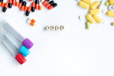 Beyaz bir masada kan testi tüplerini hapların arka planıyla karşılaştırma denetimi. Üstteki yazı için 