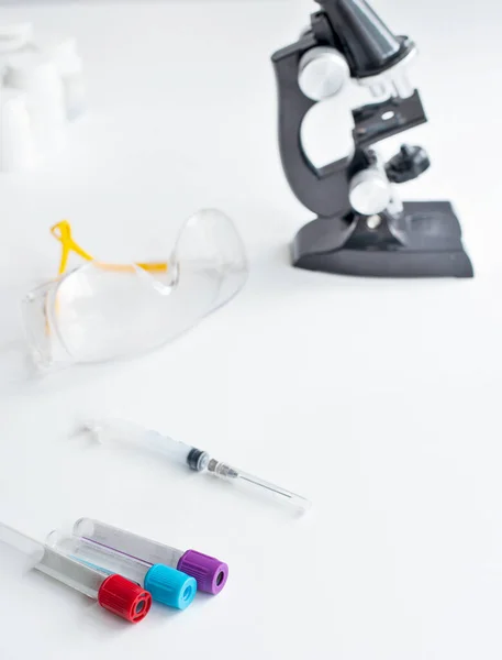Laboratory table for a blood test. Test tube glasses syringe on a white table with a microscope