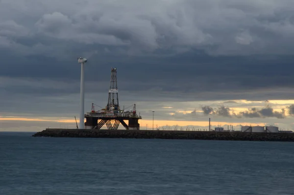 Plate-forme pétrolière et éolienne au coucher du soleil. — Photo