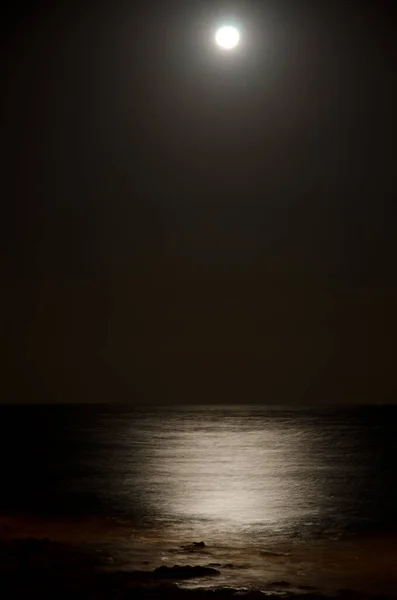Морской пейзаж ночью и луна отражаются в воде. — стоковое фото
