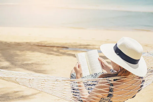 Mujer leyendo un libro sobre la playa de la hamaca en la holida del verano del tiempo libre — Foto de Stock