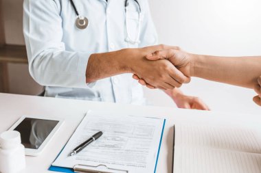 Doktor hastane ofisinde kadın hastalarıyla el sallayarak