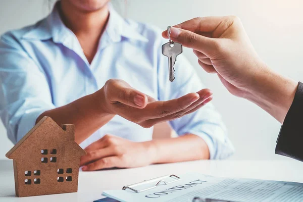 Sale Agent giving house keys to woman customer and sign agreemen