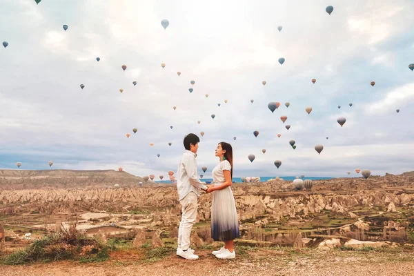 カラフルな熱気球が上空を飛んでいるのを見ているアジアのカップル — ストック写真