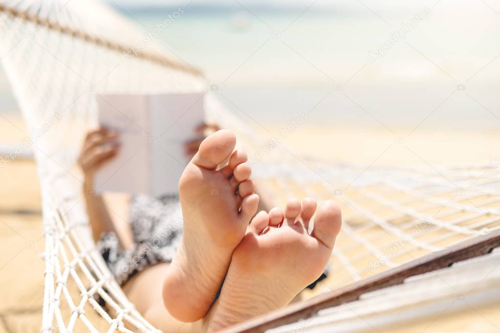 Woman reading a book on hammock beach in free time summer holida