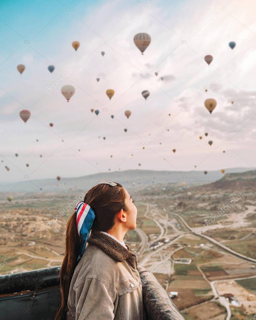 Asian woman watching colorful hot air balloons flying over the v